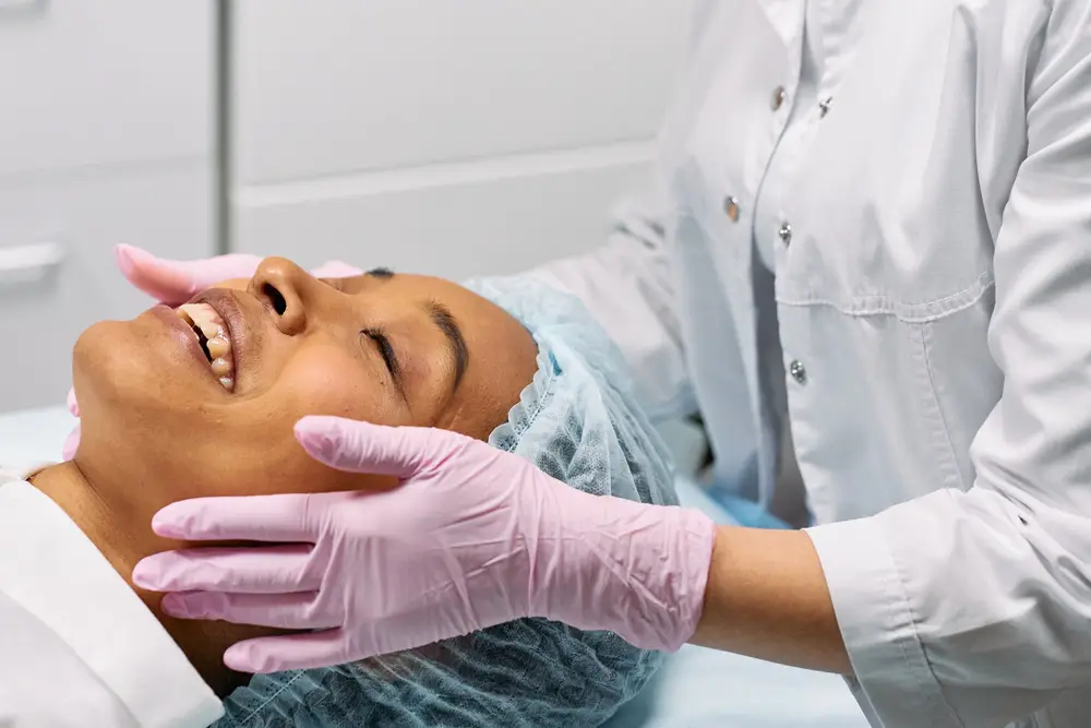 A clinician with gloved hands treating a client's face