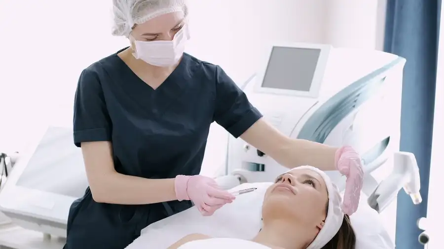 A clinician preparing a facial treatment for a client in a bright treatment room